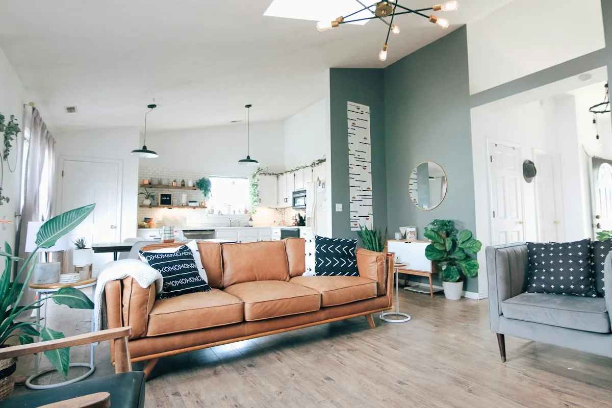 Tan leather sofa with cushions in an airy open-plan living room