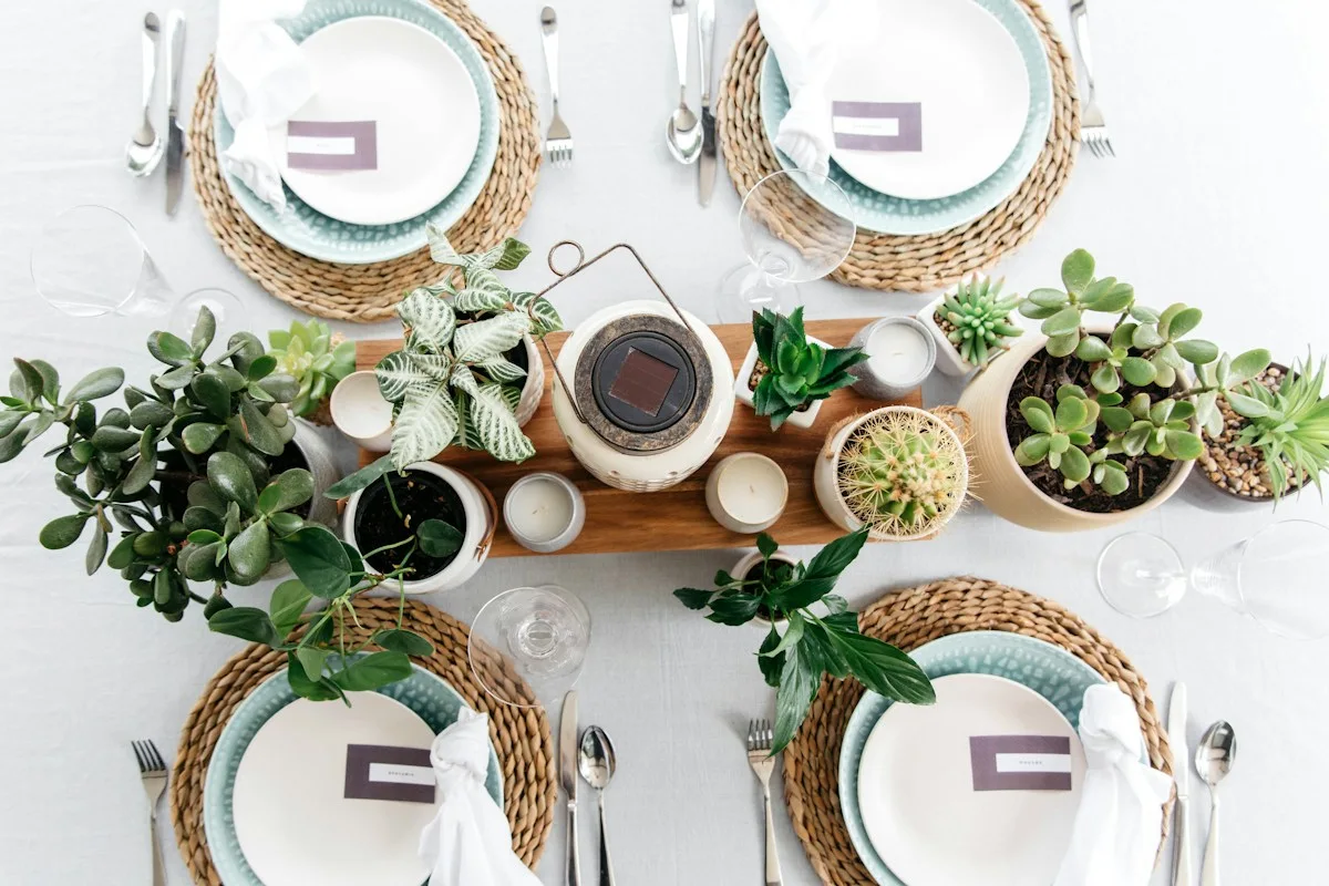 Dining table decorated with greenery, ceramic plates and glasses